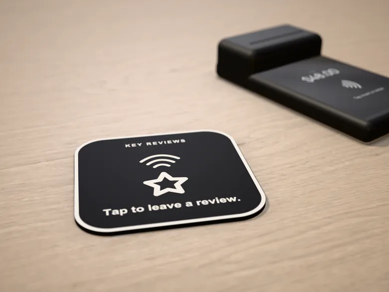 The black KEY Reviews plaque on a light wood counter. Rendered mockup.